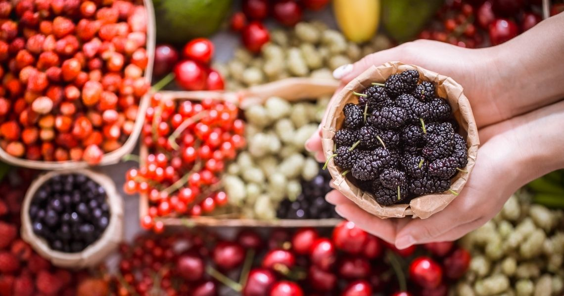 An assortment of fresh antioxidant-rich berries including mulberries, strawberries, blackberries, cherries, and red currants